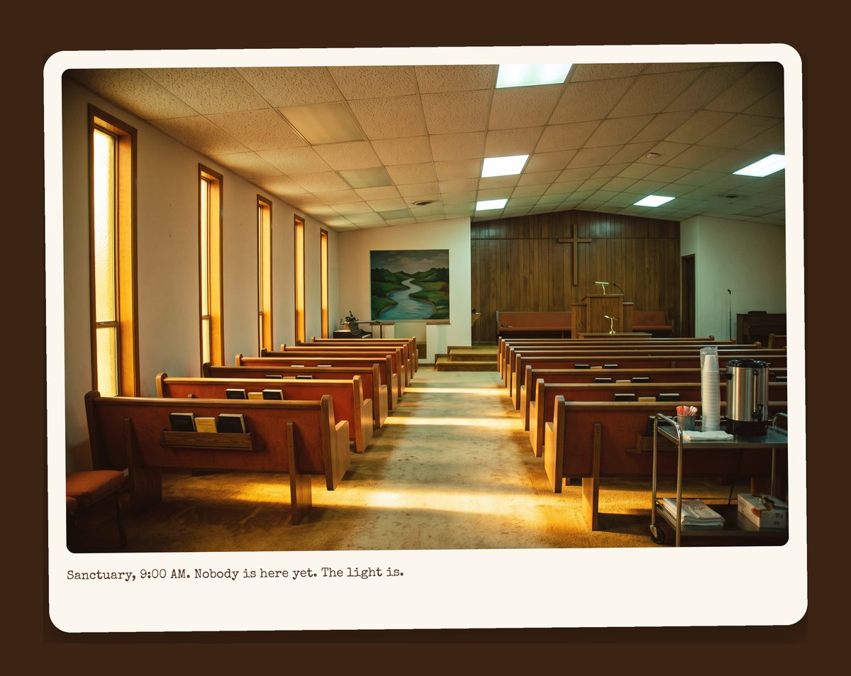 The empty sanctuary at nine in the morning: wooden pews with orange cushions, Harvest Gold carpet, amber light through the windows, the Jordan River mural at the front.